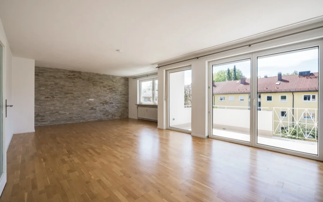 Wohnraum einer Altbauwohnung in München-Untergiesing mit Natursteinwand und Fensterfront zum Balkon — Immobilienfotografie Maximilian Sydow